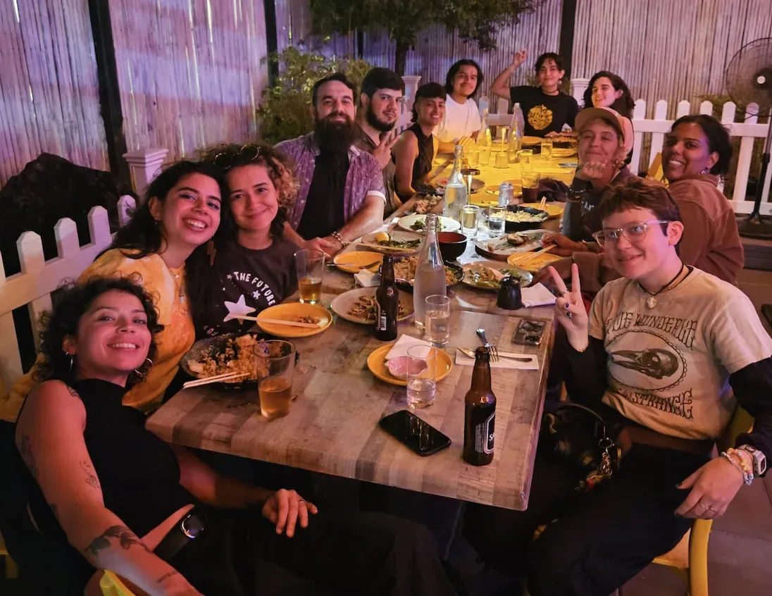 Panas around a long dinner table, leaning in together for the photo